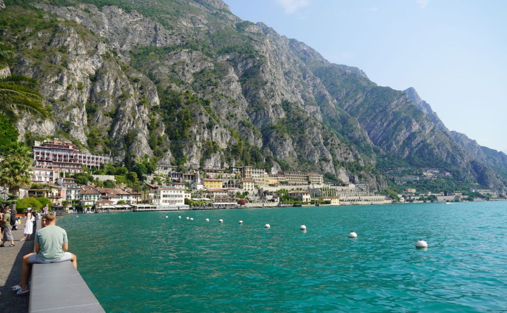 A young couple sitting by the lakeside in the town Limone sul Garda